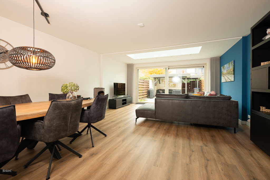 interieufotografie, interieurfoto woonkamer met een blauwe muur en een grijze bank met een tafel met stoelen