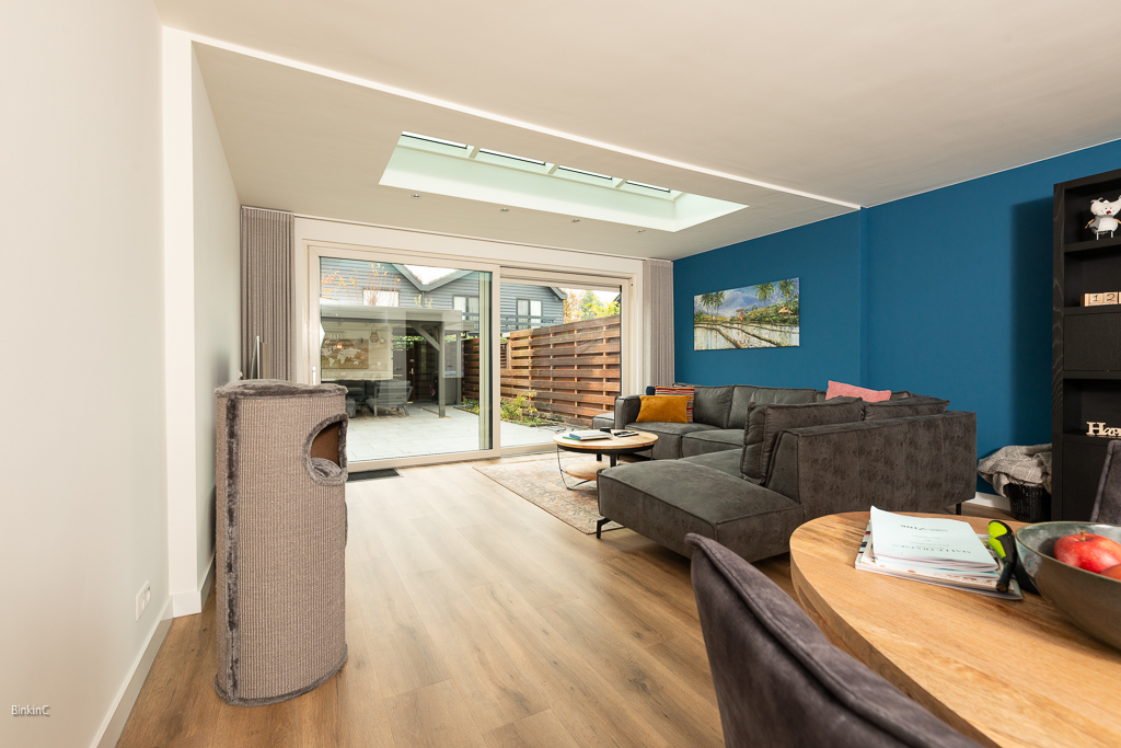 interieufotografie, interieurfoto woonkamer met een blauwe muur en een grijze bank met een tafel met stoelen